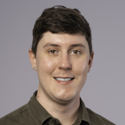 Photo of a man smilling wearing a green button-up shirt.