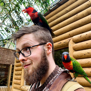 Photo of Tom Jameson with parrots on his head and shoulders