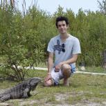 A dishevelled-looking man standing next to a lizard
